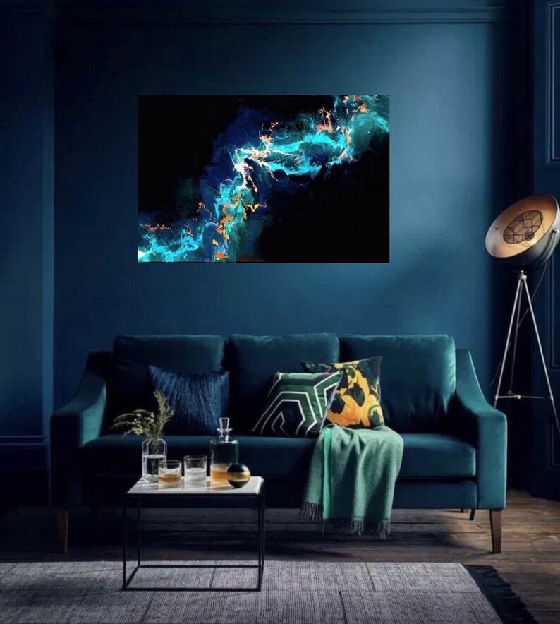 May include: Abstract painting with blue, green, and gold swirls on a black background. The painting is hanging on a dark blue wall above a teal velvet sofa with green and yellow throw pillows.