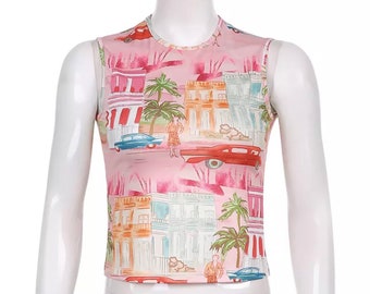 May include: Pink sleeveless tank top with a colorful print of buildings, palm trees, and cars. The print has a vintage style.