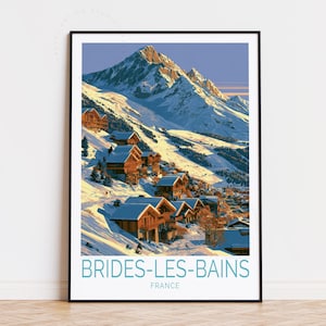 May include: A framed travel poster featuring a snowy mountain landscape with wooden chalets nestled on a slope. The text BRIDES-LES-BAINS and FRANCE is printed in blue at the bottom. The scene depicts a bright, sunny day with blue skies.