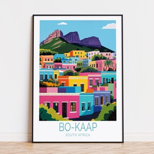 Può includere: Un'illustrazione colorata di una città con case dai colori vivaci e una catena montuosa sullo sfondo. Il testo "BO-KAAP" e "SOUTH AFRICA" è stampato sotto l'immagine.