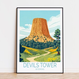 Może przedstawiać: Oprawiony wydruk przedstawiający Devils Tower w Wyoming. Ilustracja przedstawia charakterystyczną formację skalną w odcieniach brązu i pomarańczy, otoczoną zielonymi drzewami i krętą ścieżką. Tekst "Devils Tower Wyoming" znajduje się na dole.