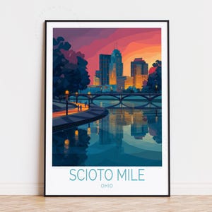 May include: A framed art print featuring a stylized illustration of the Scioto Mile in Ohio. The artwork depicts a cityscape with buildings, a bridge, and a river reflecting the sunset's colors. The text "SCIOTO MILE OHIO" is at the bottom.