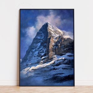 Puede incluir: Una impresión enmarcada de un pico de montaña cubierto de nieve. La obra de arte presenta un estilo de pintura dramático y texturizado con una paleta de colores de azules, blancos y marrones. La montaña está iluminada por la luz del sol, creando un contraste con el cielo nublado más oscuro.