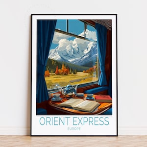 May include: A framed art print depicting the interior of the Orient Express train, with a mountain landscape visible through a window. The image features a table with a teapot, cups, and an open book, framed by blue curtains. The text "ORIENT EXPRESS EUROPE" is at the bottom.