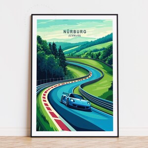 Op de afbeelding: Een ingelijste kunstdruk met een blauwe sportwagen op het circuit van de Nürburgring in Duitsland. Het kunstwerk heeft een gestileerd ontwerp met levendige kleuren, waaronder groene heuvels, een blauwe baan en de tekst "Nürburg Germany".
