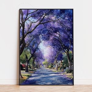 Peut inclure: Une peinture &agrave; l'aquarelle encadr&eacute;e repr&eacute;sente une rue bord&eacute;e d'arbres aux fleurs violettes. L'&oelig;uvre pr&eacute;sente une route menant au loin, avec des maisons visibles. La peinture est dans un cadre noir.
