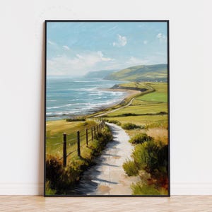 Puede incluir: Pintura de paisaje costero enmarcada en negro. La obra representa un camino que conduce al mar, con campos verdes y colinas. El cielo es azul con nubes, y el mar es una mezcla de azul y blanco. La pintura está en un marco negro.