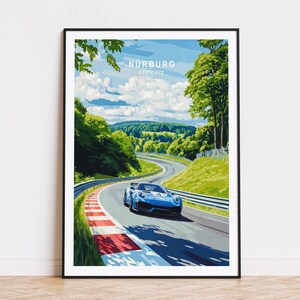 Könnte beinhalten: Ein gerahmter Kunstdruck mit einem blauen Sportwagen auf der Rennstrecke Nürburgring in Deutschland. Das Kunstwerk hat ein stilisiertes Design mit grünen Bäumen, blauem Himmel und dem Text "Nürburg Germany".