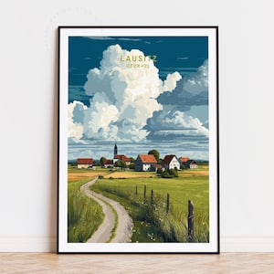 May include: Framed art print of a rural landscape in the Lausitz region of Germany. The artwork depicts a winding dirt road leading to a village with red-roofed houses, a church, and a field under a cloudy sky. The text "LAUSITZ GERMANY" is at the top.