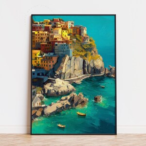 May include: A framed art print showing a coastal village with colourful buildings on a cliff. The artwork features a vibrant turquoise sea, rocky formations, and small boats, creating a scenic landscape.