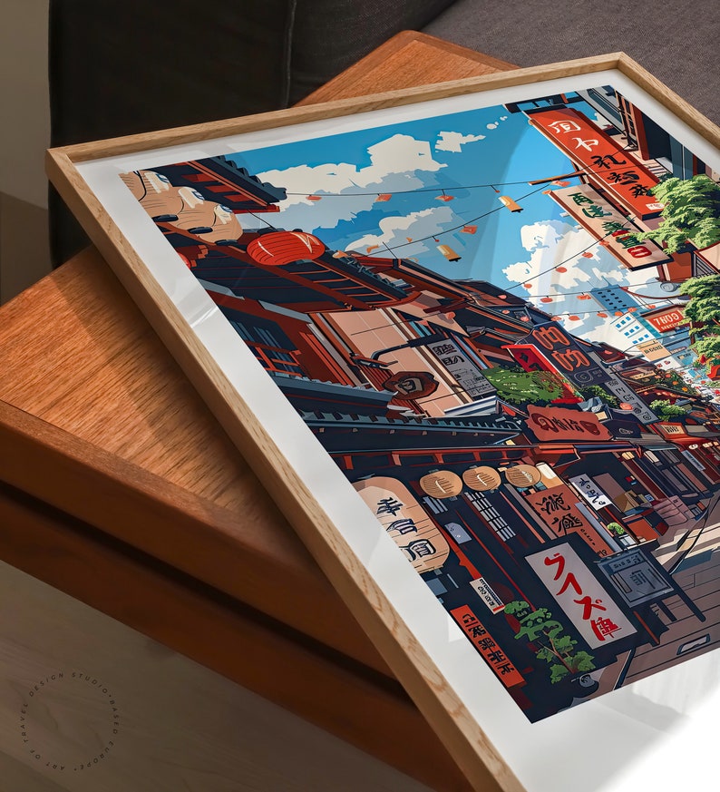 May include: A framed illustration depicting a Japanese street scene with colourful buildings, lanterns, and signs. The street is lined with shops and restaurants, and people are walking around. The sky is blue and there are clouds in the distance.