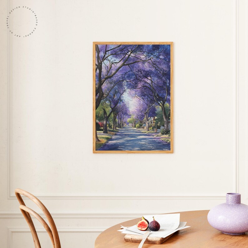 Peut inclure: Une impression d'art encadr&eacute;e repr&eacute;sentant une rue bord&eacute;e d'arbres &agrave; fleurs violettes. L'&oelig;uvre pr&eacute;sente une route menant au loin, encadr&eacute;e par les branches des arbres. L'impression est dans un cadre en bois et est accroch&eacute;e &agrave; un mur blanc.