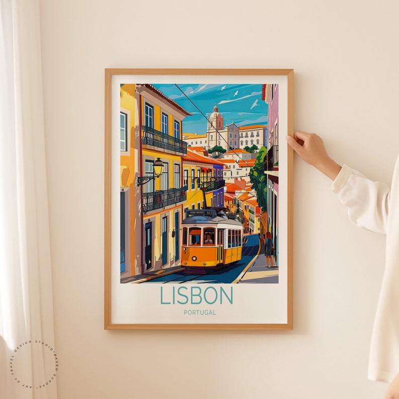 May include: A framed illustration of a yellow tram traveling up a hill in Lisbon, Portugal. The tram is surrounded by colorful buildings and a blue sky with white clouds. The text "LISBON PORTUGAL" is printed below the tram.
