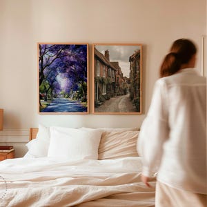Peut inclure: Deux impressions encadr&eacute;es sont accroch&eacute;es au-dessus d'un lit. L'une repr&eacute;sente une rue bord&eacute;e d'arbres &agrave; fleurs violettes. L'autre montre une rue pav&eacute;e avec des b&acirc;timents en briques. Les deux sont dans des cadres en bois clair.