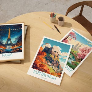 Peut inclure: Trois impressions d'art de voyage encadr&eacute;es sur une table en bois. L'une repr&eacute;sente la Tour Eiffel &agrave; Paris, France. Les deux autres montrent des paysages avec le texte "Edinburgh Scotland" et "Park". Une chaise en bois et des fournitures d'art sont &eacute;galement sur la table.