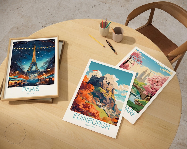 Peut inclure: Trois impressions d'art de voyage encadr&eacute;es sur une table en bois. L'une repr&eacute;sente la Tour Eiffel &agrave; Paris, France. Les deux autres montrent des paysages avec le texte "Edinburgh Scotland" et "Park". Une chaise en bois et des fournitures d'art sont &eacute;galement sur la table.