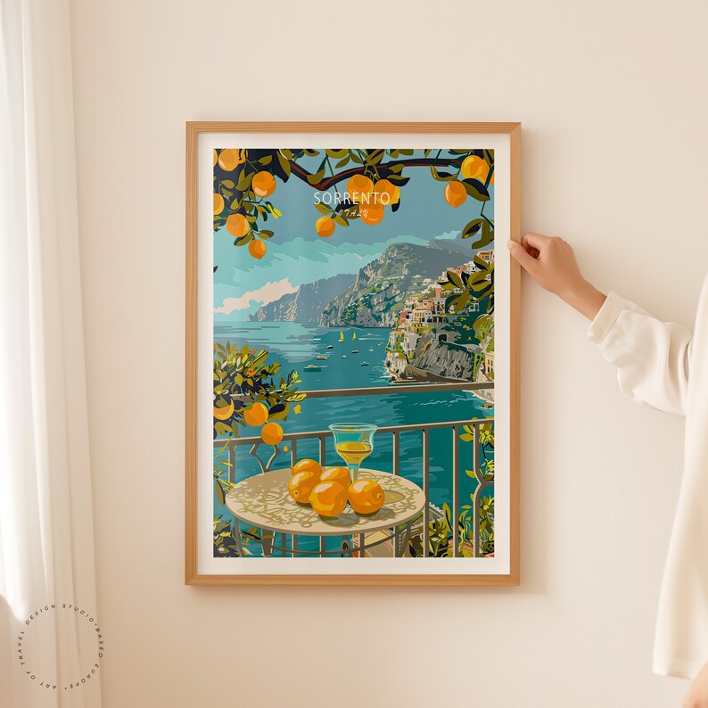 May include: A framed print of a colorful illustration depicting a view of Sorrento, Italy. The illustration features a balcony overlooking the Mediterranean Sea with a glass of lemonade and lemons on a table. The text "SORRENTO" and "ITALIA" is visible in the image.