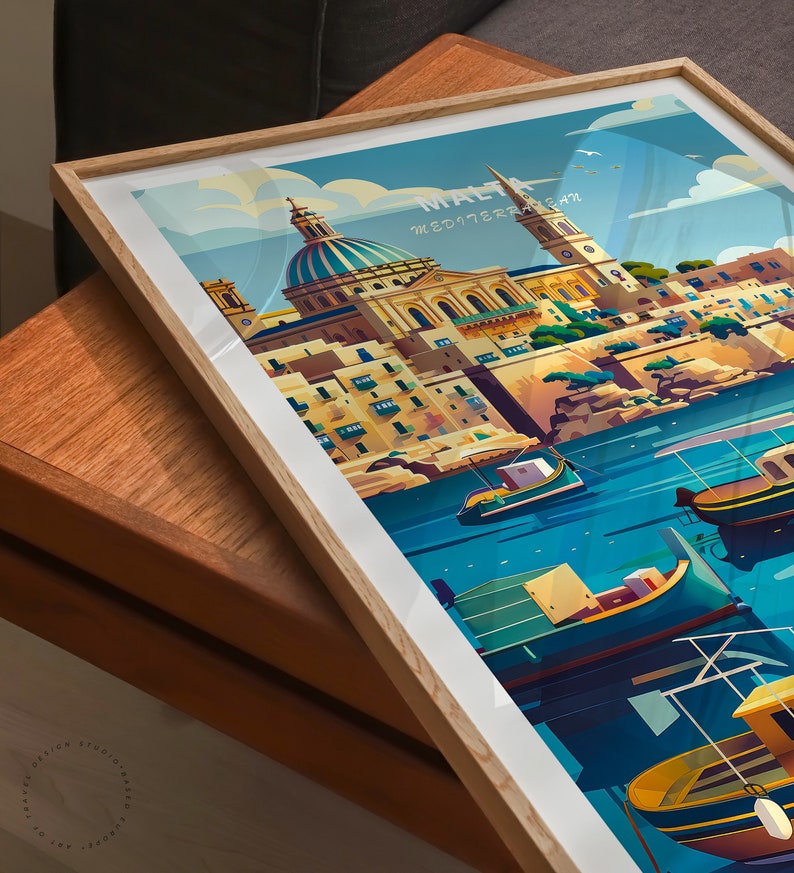 Puede incluir: L&aacute;mina art&iacute;stica enmarcada con una ilustraci&oacute;n estilizada de Malta. La obra representa una ciudad costera con un edificio con c&uacute;pula, un campanario y barcos coloridos en el agua. La impresi&oacute;n est&aacute; en un marco de madera clara.