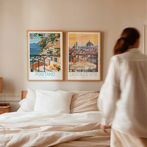 May include: Two framed travel posters on a bedroom wall. The poster on the left shows a colorful scene of Positano, Italy, with the text "Positano" below the image. The poster on the right shows a cityscape of Florence, Italy, with the text "La Dolce Vita" below the image.
