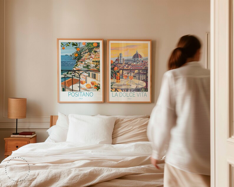 May include: Two framed travel posters on a bedroom wall. The poster on the left shows a colorful scene of Positano, Italy, with the text "Positano" below the image. The poster on the right shows a cityscape of Florence, Italy, with the text "La Dolce Vita" below the image.