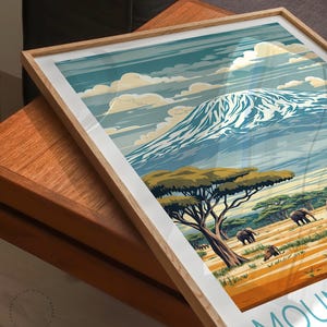 May include: A framed print of a mountain landscape with a snowy peak, green trees, and elephants in the foreground. The print has a vintage travel poster style with the text "Mount" at the bottom.
