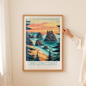 K&ouml;nnte beinhalten: Eine gerahmte Illustration der K&uuml;ste von Oregon mit einem Sonnenuntergangshimmel, felsigen Klippen und einem Strand mit Wellen. Der Text "OREGON COAST" ist unten in der Abbildung in Blau gedruckt.