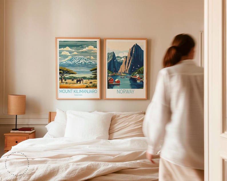 May include: Two framed travel posters on a wall above a bed with white linens. The poster on the left shows a mountain range with the text "Mount Kilimanjaro, Tanzania". The poster on the right shows a fjord with the text "Norway".
