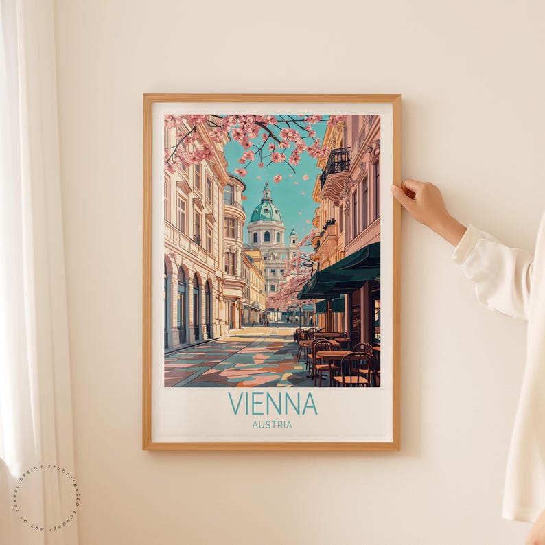 May include: A framed art print showing a street scene in Vienna, Austria. The image displays a European city street with buildings, a domed structure, and cherry blossoms. The print has the word "VIENNA" and "AUSTRIA" printed at the bottom.