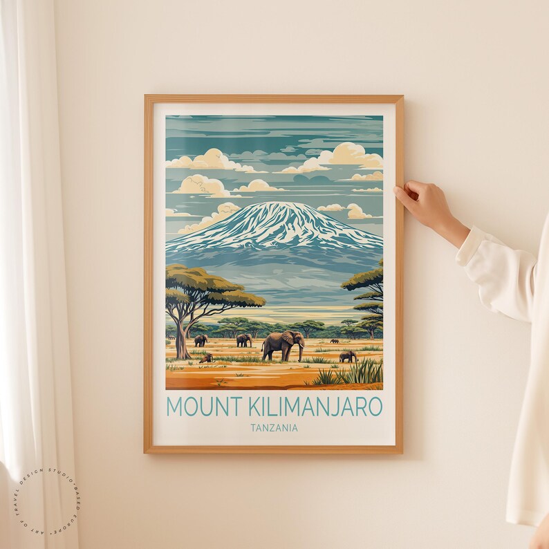 May include: A framed poster with a vintage travel illustration of Mount Kilimanjaro in Tanzania. The poster features a snowy mountain peak, green trees, and elephants in the foreground. The text "Mount Kilimanjaro, Tanzania" is printed at the bottom of the poster.
