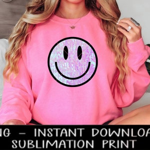 Puede incluir: Sudadera rosa con un gran gráfico de cara sonriente de lentejuelas iridiscentes.