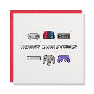 May include: A white Christmas card with a red border, featuring pixelated images of video game controllers. The text "MERRY CHRISTMAS!" is displayed in a pixelated font. A festive card for gamers.