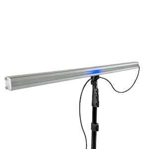 May include: A silver LED light bar with a blue light at one end, mounted on a black stand. The light bar is rectangular and has a sleek, modern design. A black cable is connected to the light.