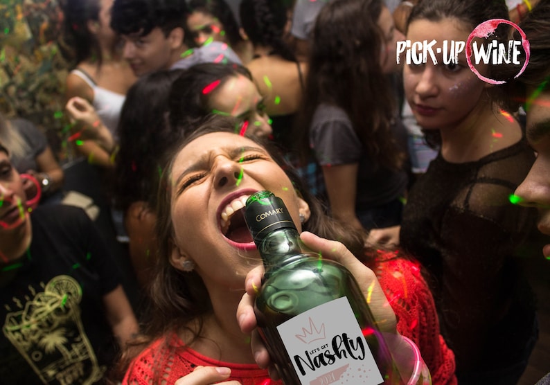 May include: A group of people at a party, one person is holding a bottle of wine with a label that says "Let's Get Nasty".