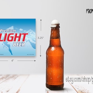 May include: A blue and white beer label with the text "Premium Light Beer" and a mountain scene. The label is 4 inches wide and 3.25 inches tall. A brown glass beer bottle with a white foam head is shown next to the label.