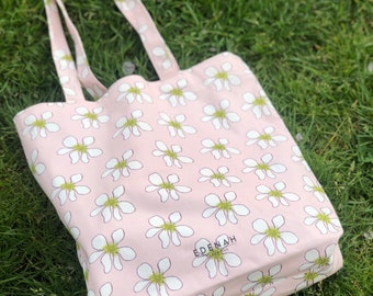 May include: A pink tote bag with a white floral pattern and the text "EDENAH DESIGNS" printed on the front.