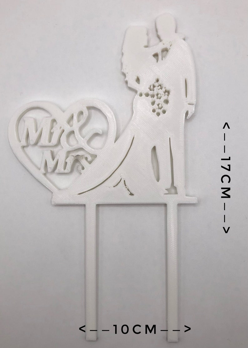Pu&ograve; includere: Topper per torta in plastica bianca con una silhouette di sposa e sposo con un cuore che dice "Mr & Mrs". Il topper &egrave; alto 17 cm e largo 10 cm.