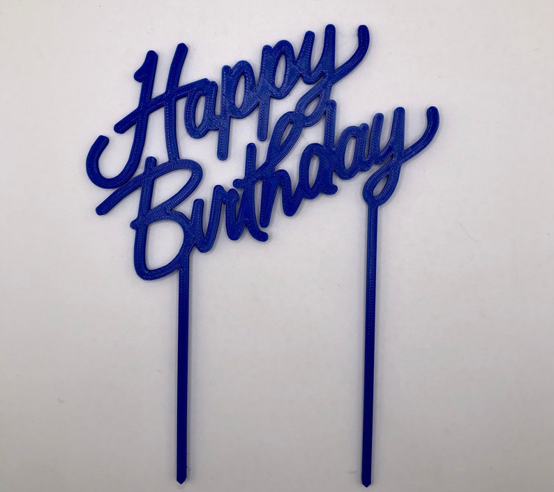May include: Blue plastic cake topper with the words "Happy Birthday" in a cursive font.