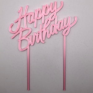 May include: Pink cake topper with the words "Happy Birthday" in a cursive font.