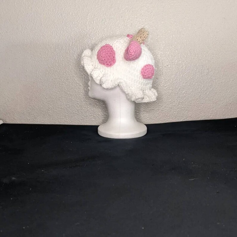 May include: White crocheted hat with pink polka dots and a small white pom-pom on top.