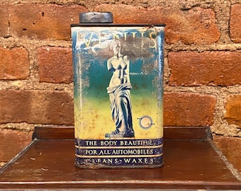 Peut inclure: Boîte en métal vintage avec un design bleu et jaune représentant une silhouette de femme. Le texte sur la boîte indique "The Body Beautiful For All Automobiles Cleans & Waxes".
