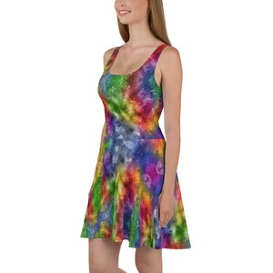 May include: A sleeveless skater dress featuring a vibrant, multi-colored tie-dye pattern with swirling hues of red, yellow, green, blue, and purple. The dress has a scoop neckline and a fitted bodice that flares out into a circular skirt.
