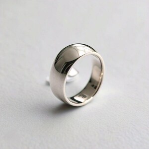 May include: A silver wedding band with a rounded, polished surface.