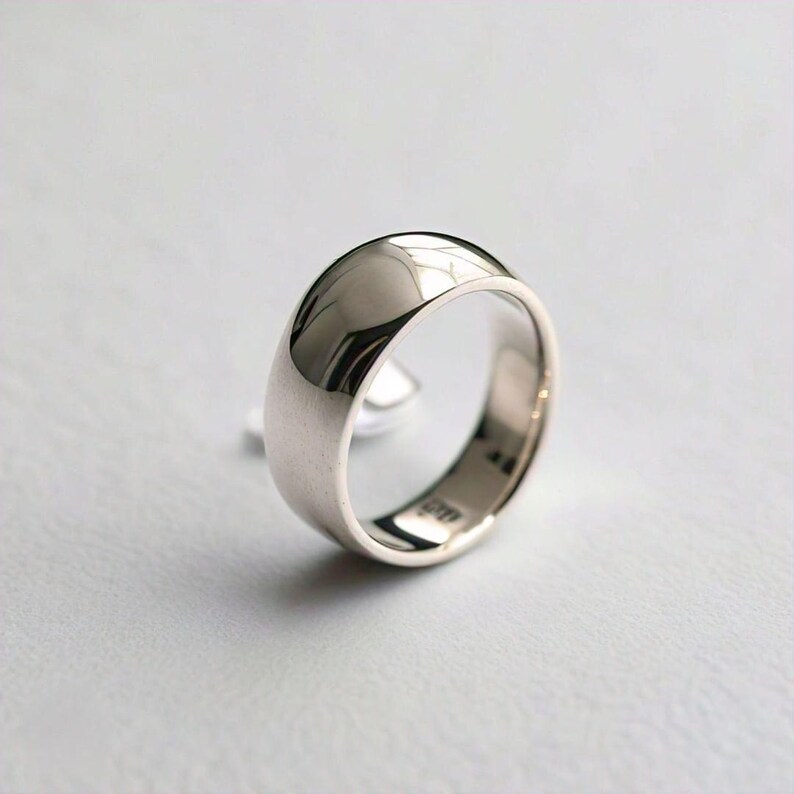 May include: A silver wedding band with a rounded, polished surface.
