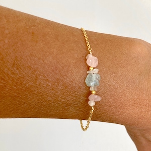 May include: A gold chain bracelet with pink and blue gemstone beads.