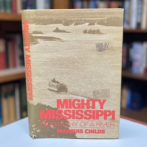 May include: A vintage book titled "Mighty Mississippi! Biography of a River" by Marquis Childs. The cover features a photo of a river with a boat and trees in the background.