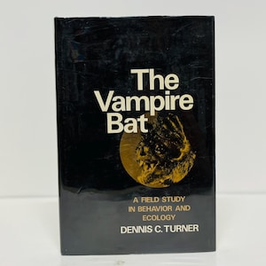 May include: A vintage book titled "The Vampire Bat" with a black cover. The title is in white, with a gold illustration of a bat's face. The book also includes the text "A Field Study in Behavior and Ecology" and the author's name.