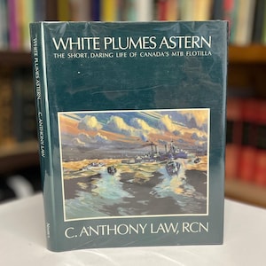 Op de afbeelding: Een hardcover boek getiteld "WHITE PLUMES ASTERN" met een donkergroene kaft. Het boek bevat een illustratie van boten op het water. De naam van de auteur, C. Anthony Law, staat op de kaft.