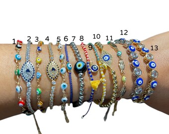 May include: Thirteen different evil eye bracelets with various styles and colors. Some bracelets feature a single evil eye charm, while others have multiple charms. The bracelets are made with different materials, including beads, string, and metal.
