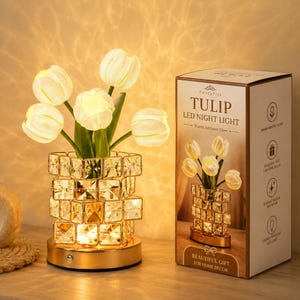 May include: A Tulip LED Night Light featuring five white tulip-shaped bulbs emerging from a square, faceted crystal-style base on a gold-toned circular stand. The packaging box displays the product name and features a warm ambient glow.