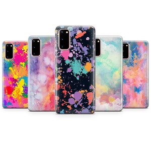Könnte beinhalten: Fünf verschiedene Handyhüllen mit bunten Farbklecks-Designs. Die Hüllen sind transparent und zeigen das Handy durch das Design. Die Designs umfassen einen schwarzen Hintergrund mit bunten Farbklecksen, ein Aquarell-Design in Rosa-, Blau- und Gelbtönen sowie ein pink- und orangenes Design mit Aquarelleffekt.